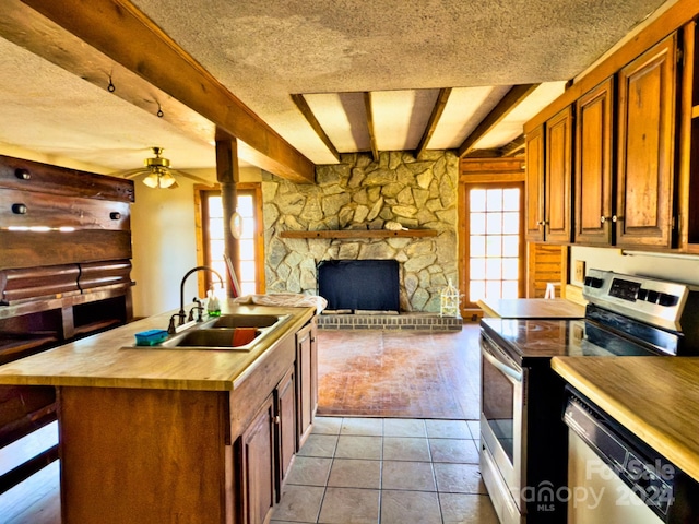 kitchen with beam ceiling, sink, stainless steel appliances, and a textured ceiling