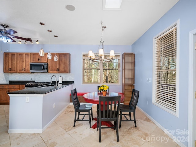 dining room featuring light tile patterned floors, ceiling fan with notable chandelier, a healthy amount of sunlight, and sink