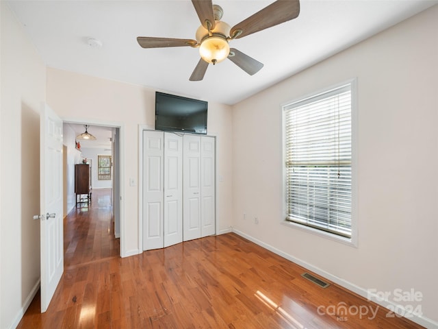 unfurnished bedroom with hardwood / wood-style flooring, ceiling fan, and a closet