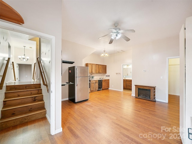 unfurnished living room with ceiling fan with notable chandelier and light hardwood / wood-style floors