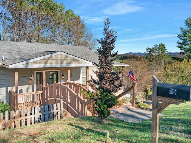 view of front of property featuring a mountain view, a porch, and a front lawn