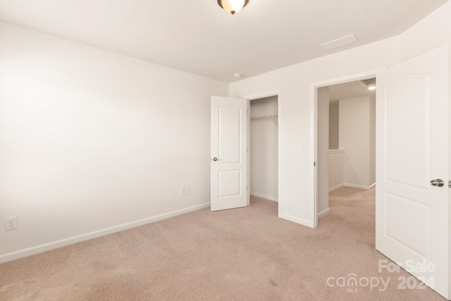 unfurnished bedroom with light carpet and a closet