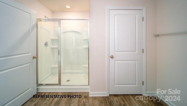 bathroom with a shower with door and wood-type flooring