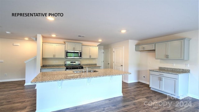 kitchen with sink, stainless steel appliances, an island with sink, and dark wood-type flooring