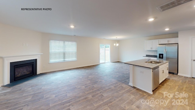 kitchen with stainless steel appliances, white cabinetry, a kitchen island with sink, and light hardwood / wood-style flooring