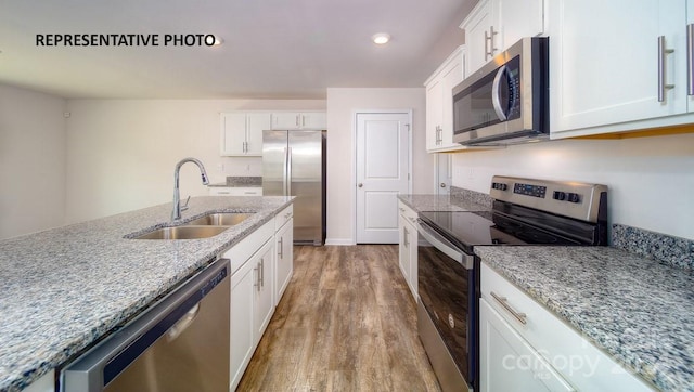 kitchen featuring white cabinetry, sink, stainless steel appliances, and light wood-type flooring