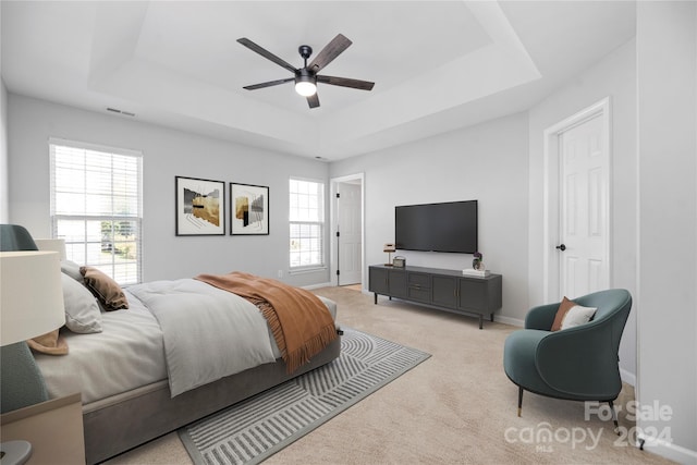 carpeted bedroom featuring ceiling fan and a raised ceiling