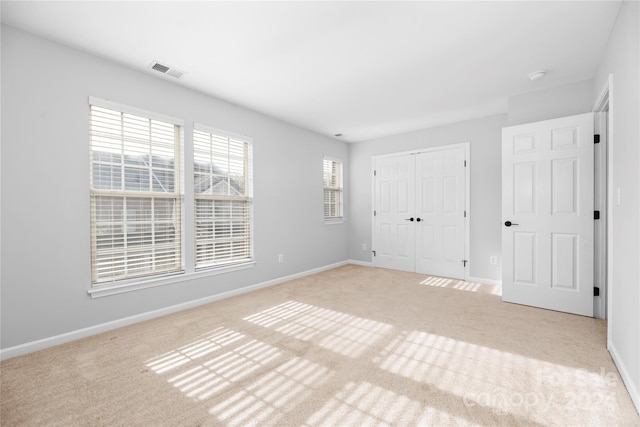 unfurnished bedroom featuring a closet and light colored carpet