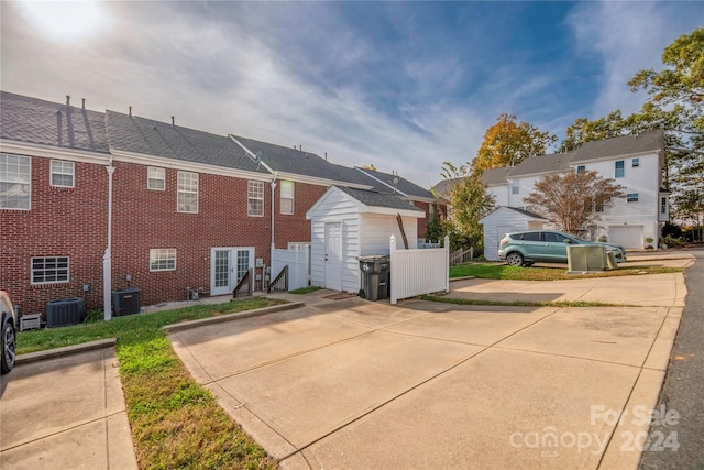 rear view of house with central AC, a garage, and french doors