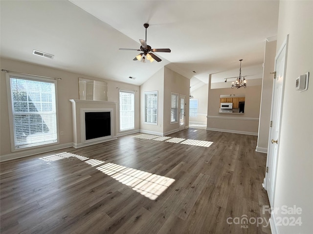 unfurnished living room featuring ceiling fan with notable chandelier, lofted ceiling, and dark wood-type flooring