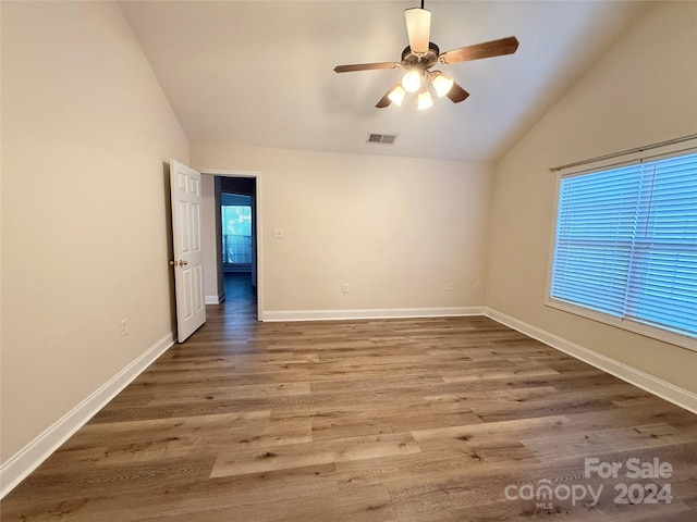 empty room featuring hardwood / wood-style floors, lofted ceiling, and a wealth of natural light