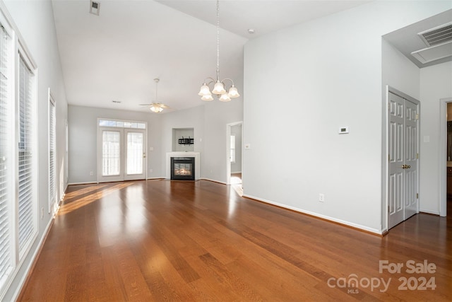 unfurnished living room with hardwood / wood-style floors, ceiling fan with notable chandelier, and high vaulted ceiling