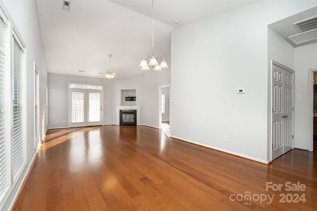 unfurnished living room featuring hardwood / wood-style flooring, ceiling fan with notable chandelier, and high vaulted ceiling