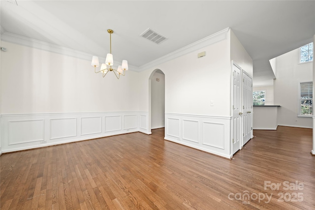 spare room featuring crown molding, hardwood / wood-style floors, and a notable chandelier