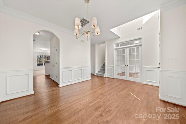 unfurnished dining area featuring ornamental molding, a notable chandelier, and hardwood / wood-style flooring