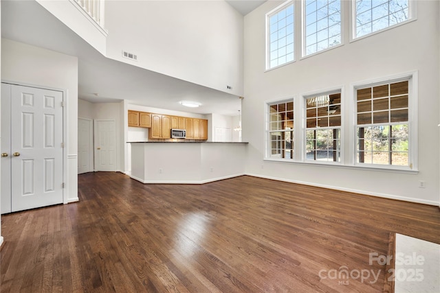 unfurnished living room featuring dark hardwood / wood-style flooring and a towering ceiling