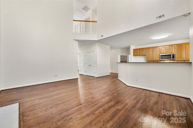 unfurnished living room featuring a high ceiling and dark hardwood / wood-style flooring