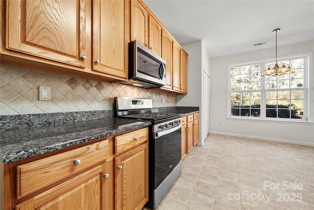 kitchen featuring dark stone counters, light tile patterned floors, decorative light fixtures, stainless steel appliances, and a chandelier