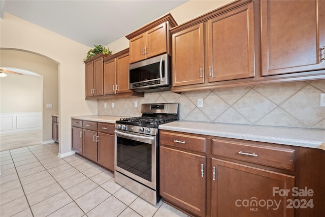 kitchen with tasteful backsplash, ceiling fan, light tile patterned flooring, and appliances with stainless steel finishes