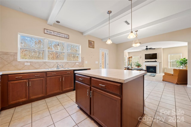 kitchen with ceiling fan, a center island, beamed ceiling, pendant lighting, and light tile patterned floors