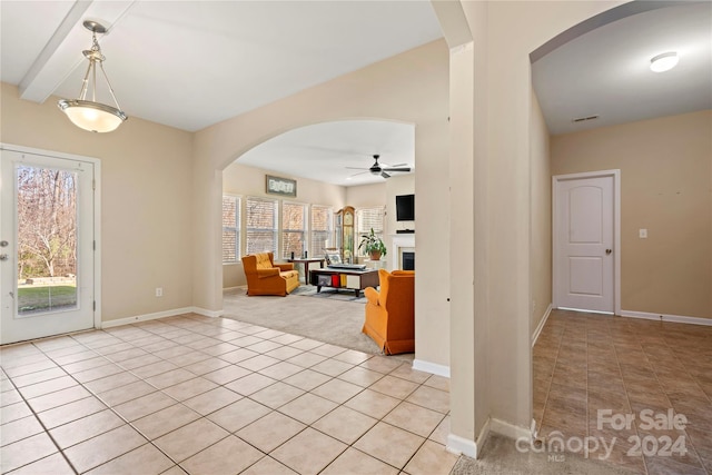 foyer with plenty of natural light, ceiling fan, light colored carpet, and beam ceiling