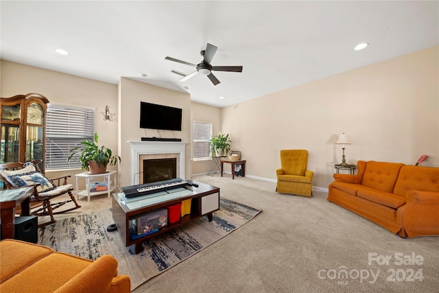 carpeted living room with ceiling fan and a fireplace