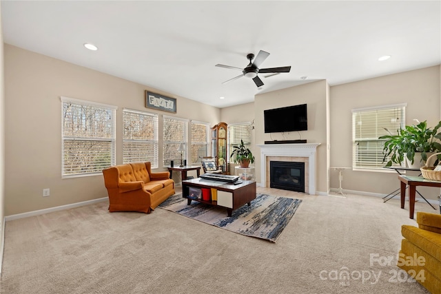 living room with ceiling fan, light colored carpet, and a tiled fireplace