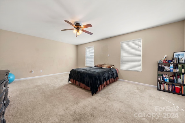 bedroom with ceiling fan, light colored carpet, and multiple windows