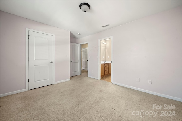 unfurnished bedroom featuring ensuite bathroom and light colored carpet