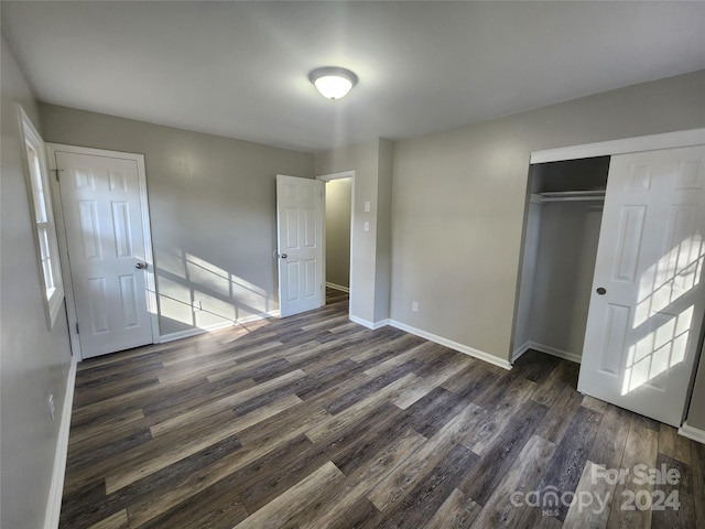 unfurnished bedroom with dark wood-type flooring and a closet