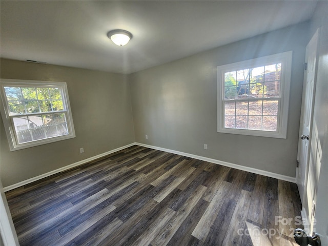 empty room with plenty of natural light and dark wood-type flooring