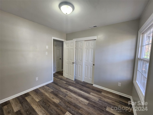 unfurnished bedroom with dark hardwood / wood-style flooring and a closet