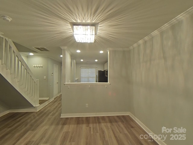 unfurnished room featuring stairs, wood finished floors, visible vents, and baseboards