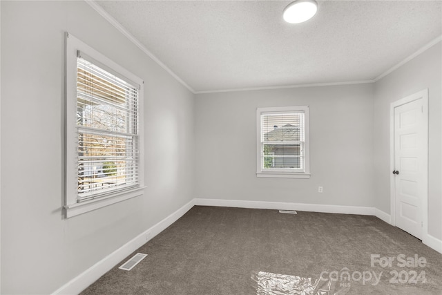 unfurnished room with dark carpet, a textured ceiling, and ornamental molding