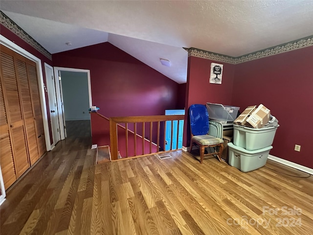 additional living space featuring a textured ceiling, hardwood / wood-style flooring, and lofted ceiling