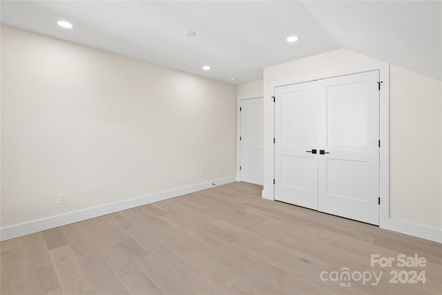 unfurnished bedroom featuring lofted ceiling, light wood-type flooring, and a closet