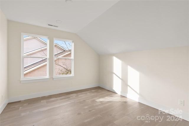 additional living space with light wood-type flooring and vaulted ceiling