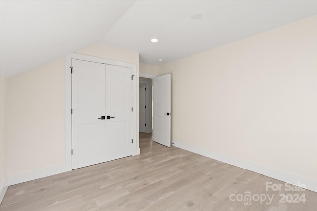 unfurnished bedroom with vaulted ceiling, light hardwood / wood-style flooring, and a closet