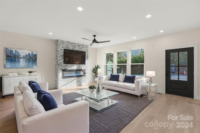 living room featuring a stone fireplace, ceiling fan, and hardwood / wood-style flooring