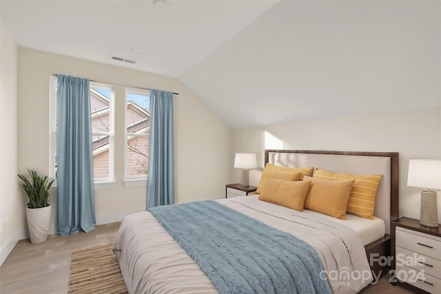 bedroom featuring light hardwood / wood-style floors and lofted ceiling