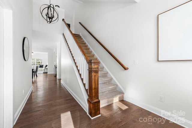 stairs featuring hardwood / wood-style flooring and a notable chandelier