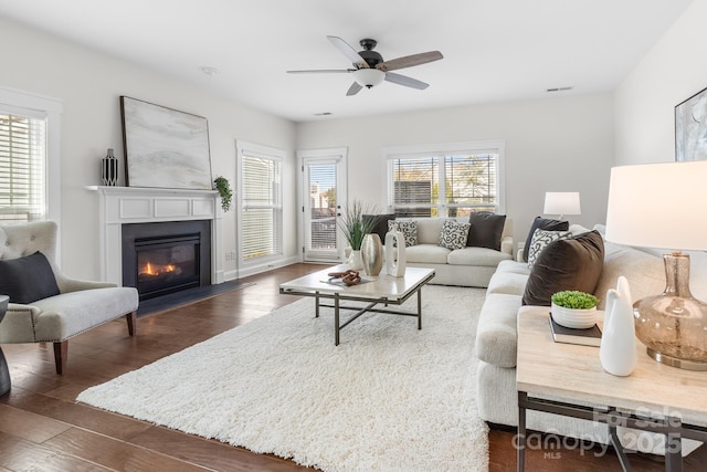 living room with plenty of natural light, ceiling fan, and dark hardwood / wood-style flooring