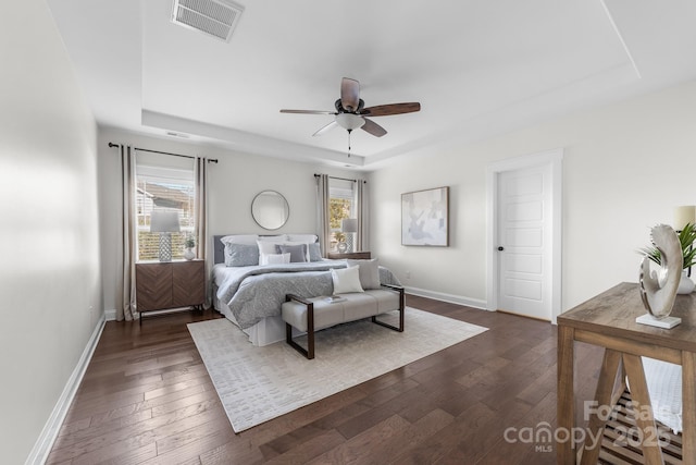 bedroom featuring ceiling fan, dark hardwood / wood-style floors, and a raised ceiling