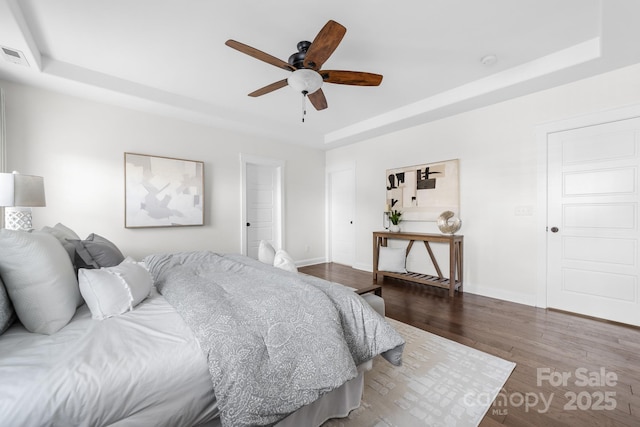 bedroom with a tray ceiling, ceiling fan, and hardwood / wood-style flooring