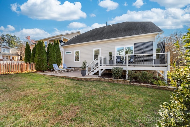 rear view of house featuring a lawn, a wooden deck, and a patio