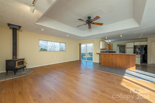 208 Dogwood Ln, Black Mountain, NC 28711 - unfurnished living room with light wood-type flooring, a wood stove, a textured ceiling, and a tray ceiling