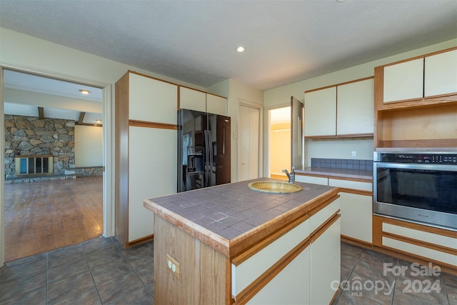 208 Dogwood Ln, Black Mountain, NC 28711 - kitchen with a center island, dark wood-type flooring, oven, black fridge, and a stone fireplace