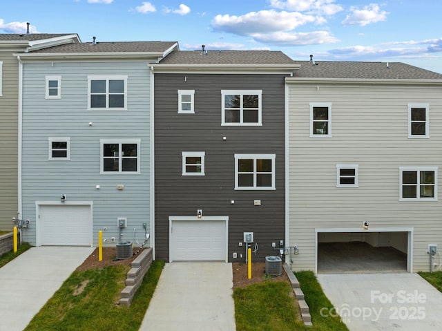 rear view of property with central AC and a garage