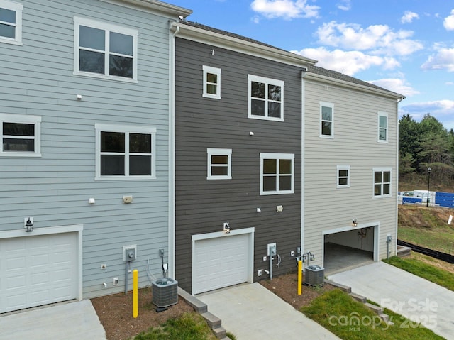 rear view of property with a garage and central air condition unit