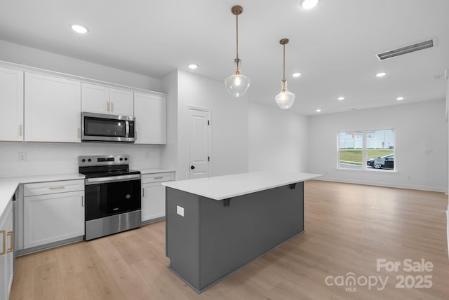 kitchen featuring a center island, hanging light fixtures, appliances with stainless steel finishes, light hardwood / wood-style floors, and white cabinets